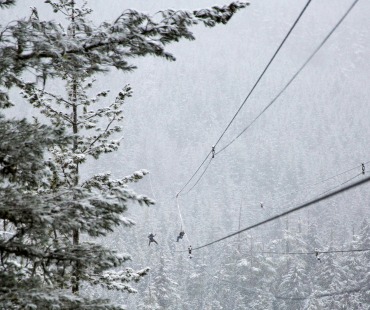 People flying on ziplines at Whistler in the winter