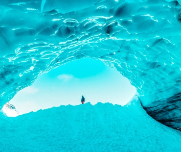 ethereal blue ice caves with skier standing in the opening