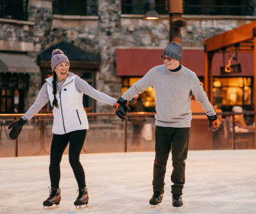 couple holding hands ice skating at Northstars outdoor rink