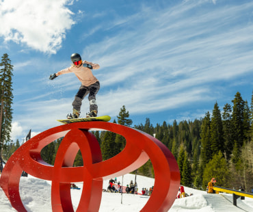 Snowboarder grinding on the toyota symbol rail