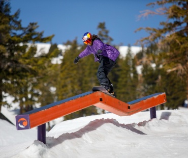 Snowboarder hitting rail at terrain park