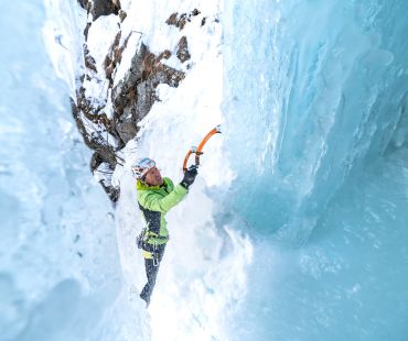 Man climbing steep frozen waterfall