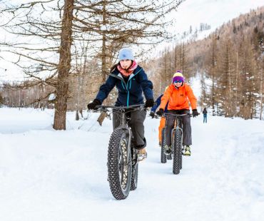 People fat biking through snow covered trails