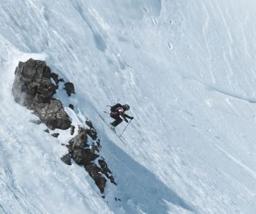 Experienced skier launching off mountain face in backcountry