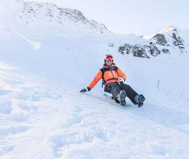 Person sledding down snowy trails