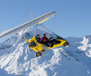 Microlight flying through the snowy valley