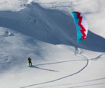 Snowboarder using a snow kite on the hill