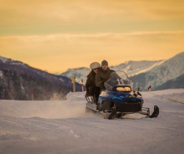 People at sunset riding on trails in snowmobile