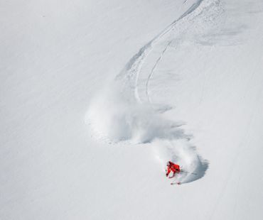 Skier carving through deep snow bowl