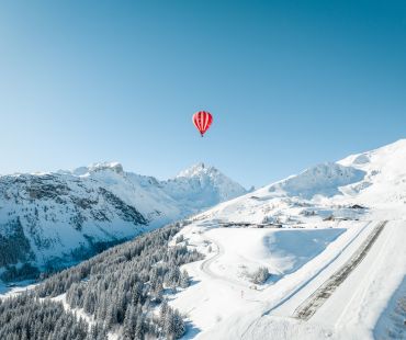 Red Hot air ballon high over the snowy mountains