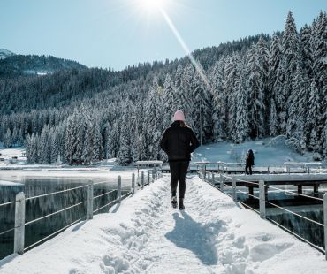 Person hiking over snowy bridge