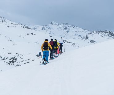 People hiking up the mountain in skis