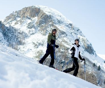 People hiking on snowy hills in snowshoes