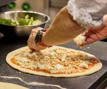 Chef sprinkling cheese on pizza dough