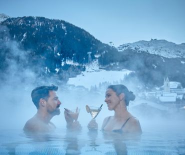 Couple enjoying cocktail in warm hot baths