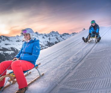 People sledding at sunset