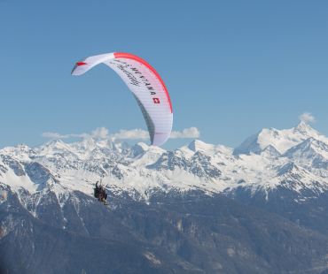 Person paragliding above the mountain peaks