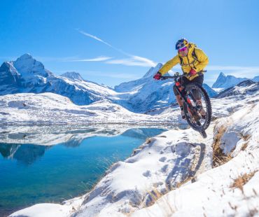 Person jumping on mountain bike in snowy trails