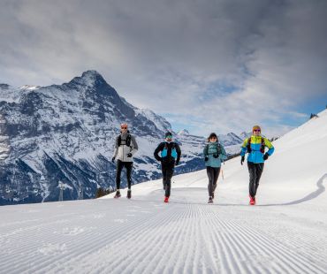 4 people running at high altitude snowy trail