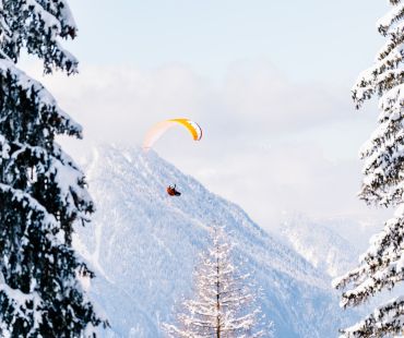 Person soaring on parachute through the snowy valley