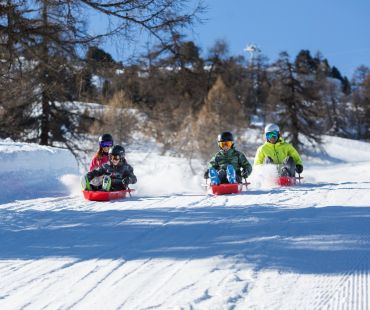 People enjoying sledding down snowy trails