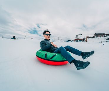 Person enjoying riding snow tube down trails